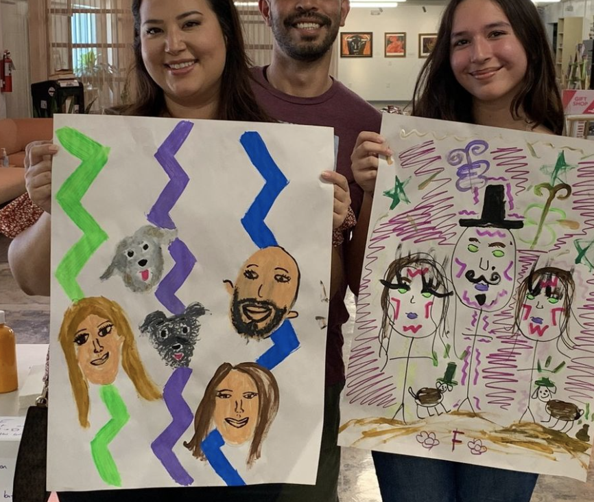 This is a photo of a family holding their family portraits during a SAY Sí Summer Saturday session.